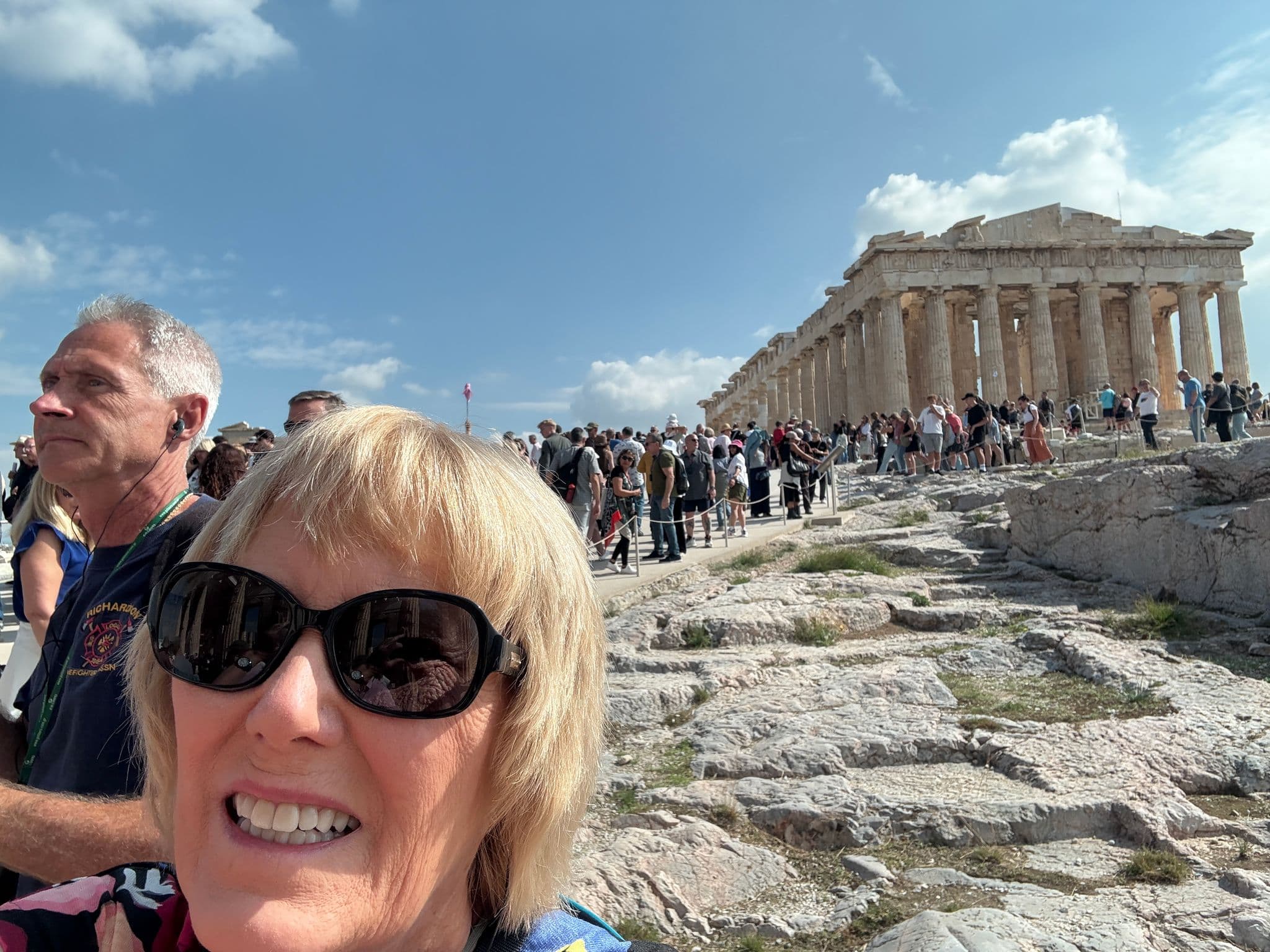 Parthenon on the Acropolis with a close selfie of a tourist and crowds on the hill, Athens, Greece.