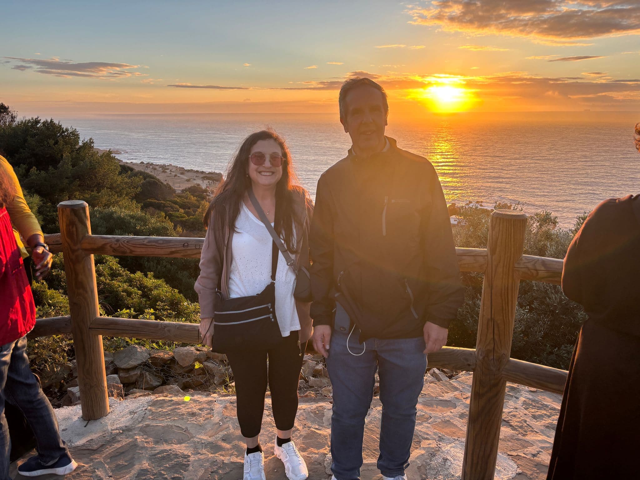 Sunset over the Strait of Gibraltar with two people standing by a wooden railing overlooking the Atlantic coast, Spain.