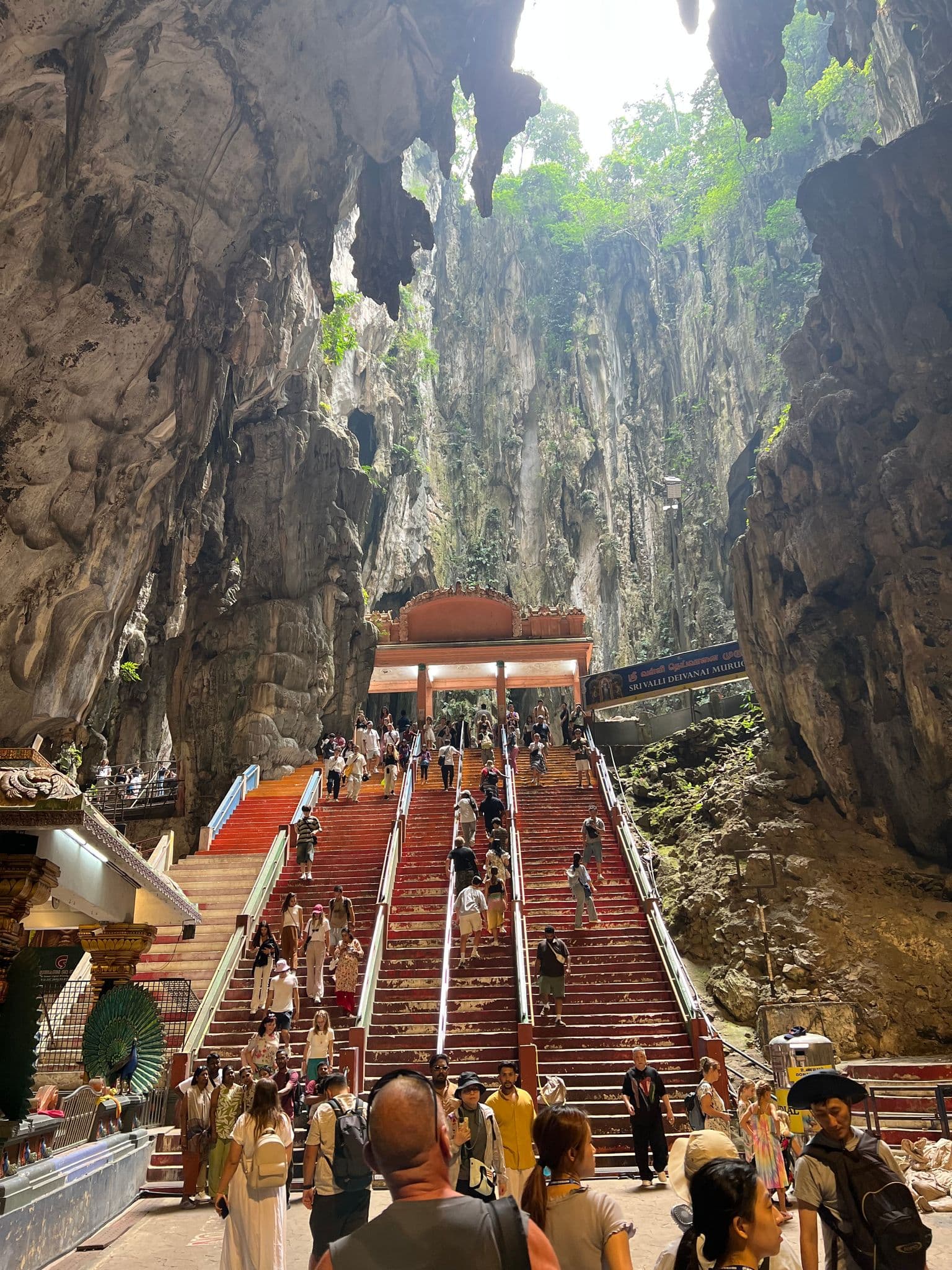 Batu Caves limestone cavern and long red staircase with many visitors climbing and walking, near Kuala Lumpur, Malaysia