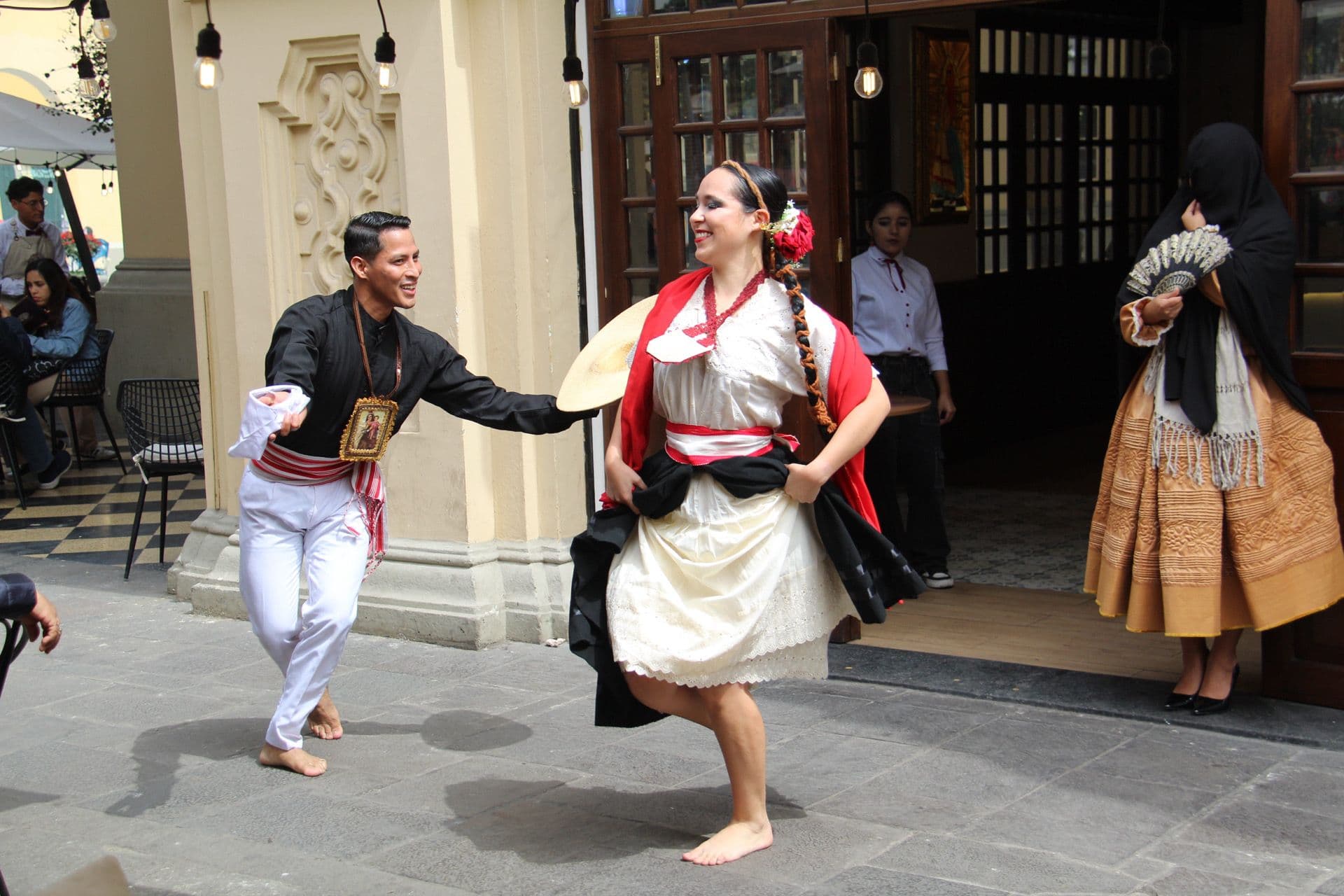 Two traditional dancers performing barefoot on a street outside a building in Lima, Peru.